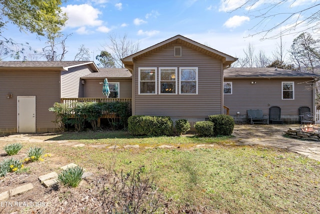 back of property with entry steps and a yard