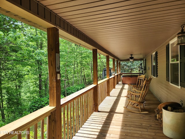deck featuring a hot tub, a forest view, and ceiling fan