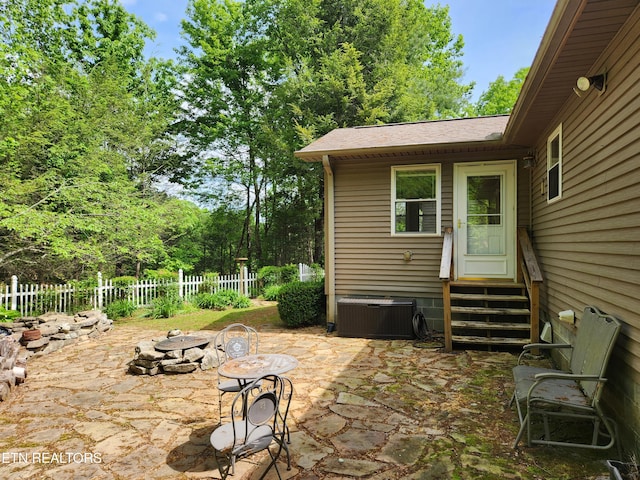 view of patio / terrace featuring an outdoor fire pit, cooling unit, entry steps, and fence