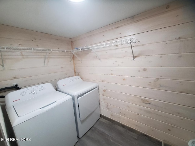 laundry area featuring laundry area, wooden walls, dark wood-style floors, and washer and clothes dryer