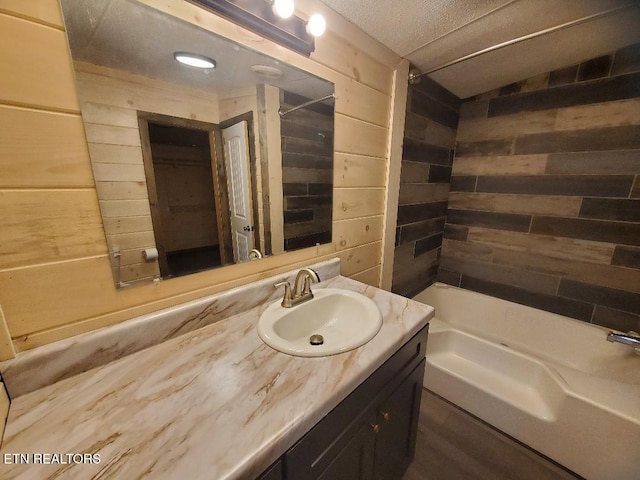 full bathroom with vanity, shower / tub combination, wooden walls, and a textured ceiling