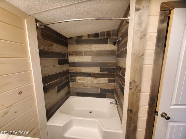 bathroom featuring wooden walls, a textured ceiling, and shower / bathtub combination