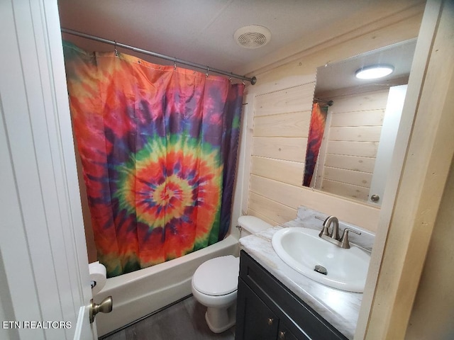 bathroom with wooden walls, toilet, vanity, and shower / tub combo