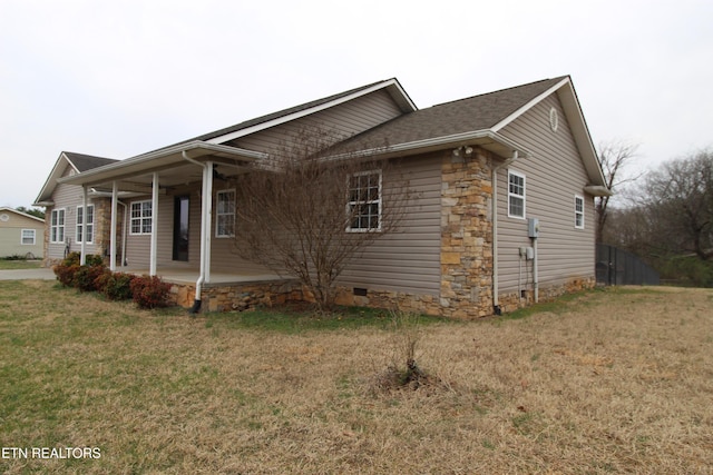 view of side of property featuring a yard, covered porch, and stone siding