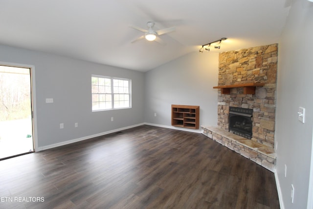 unfurnished living room featuring dark wood-style floors, baseboards, lofted ceiling, ceiling fan, and a stone fireplace