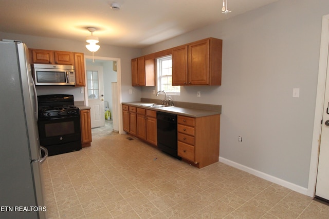 kitchen featuring baseboards, light countertops, brown cabinetry, black appliances, and a sink