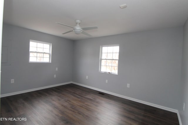 empty room with dark wood finished floors, baseboards, visible vents, and ceiling fan