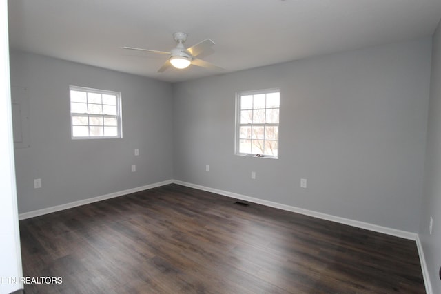 spare room featuring visible vents, baseboards, dark wood-style floors, and a ceiling fan