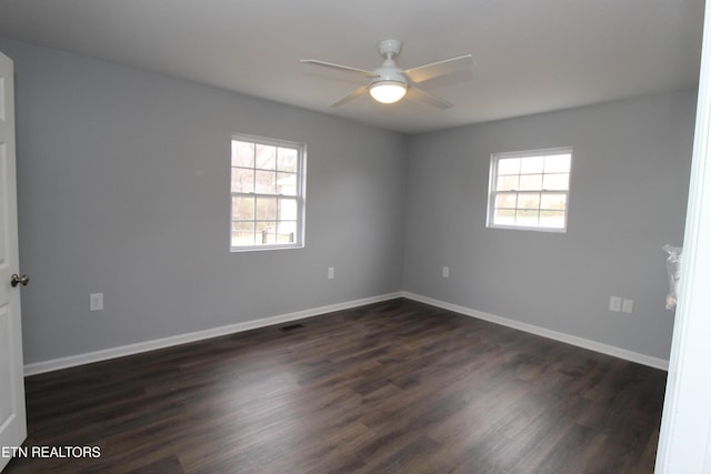 empty room featuring dark wood-style floors, baseboards, and a ceiling fan