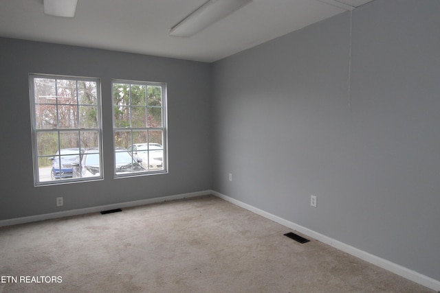 carpeted spare room featuring visible vents and baseboards