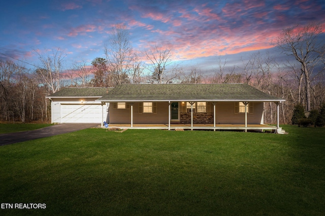 view of front of house with aphalt driveway, a lawn, a porch, and a garage