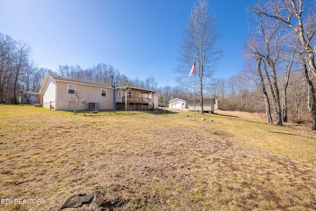 view of yard featuring an outdoor structure, central air condition unit, a garage, and a wooden deck