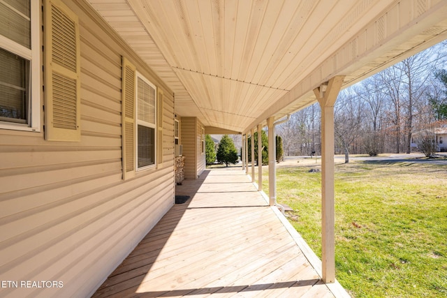 wooden terrace featuring a lawn and a porch