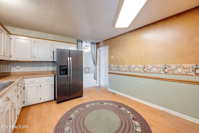 kitchen featuring white cabinetry, light wood-style flooring, stainless steel fridge with ice dispenser, and a textured ceiling