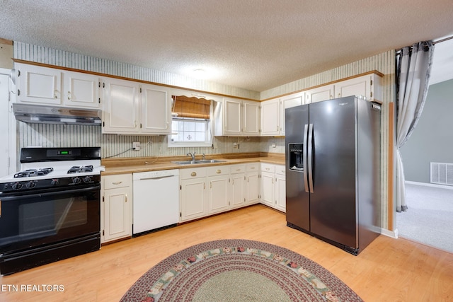 kitchen with range with gas cooktop, under cabinet range hood, white dishwasher, black fridge with ice dispenser, and a sink