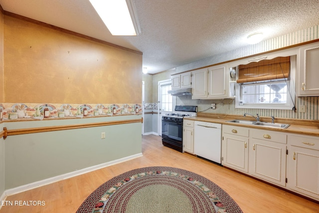 kitchen with under cabinet range hood, gas range, light wood-style floors, white dishwasher, and a sink