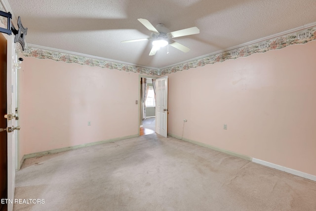 carpeted empty room with ornamental molding, a ceiling fan, baseboards, and a textured ceiling