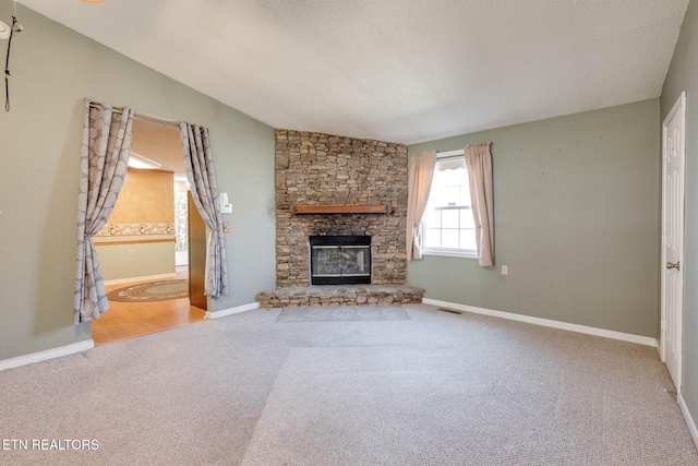 unfurnished living room with visible vents, a textured ceiling, carpet flooring, a fireplace, and vaulted ceiling