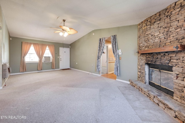 unfurnished living room with lofted ceiling, a textured ceiling, a stone fireplace, baseboards, and ceiling fan