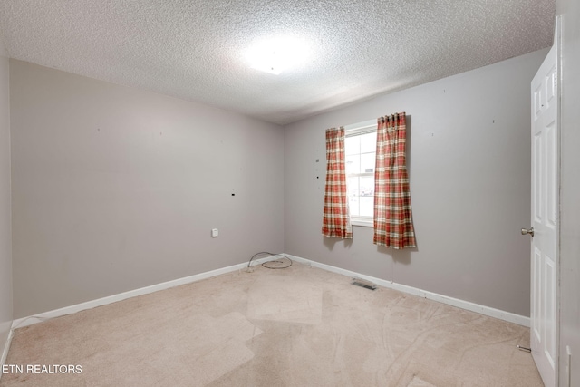 spare room featuring visible vents, baseboards, carpet, and a textured ceiling