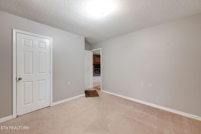 unfurnished bedroom with a textured ceiling, baseboards, and light carpet