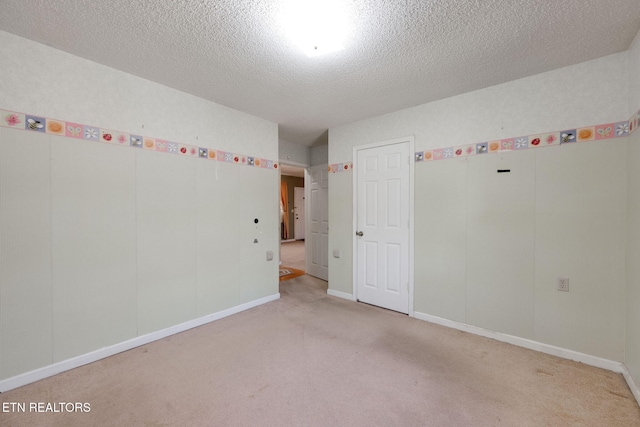 unfurnished room featuring light carpet, a textured ceiling, and baseboards