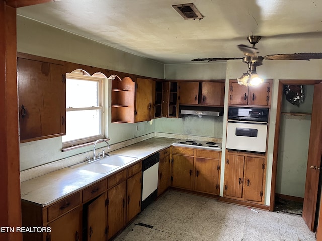 kitchen featuring brown cabinets, a sink, under cabinet range hood, white appliances, and light floors