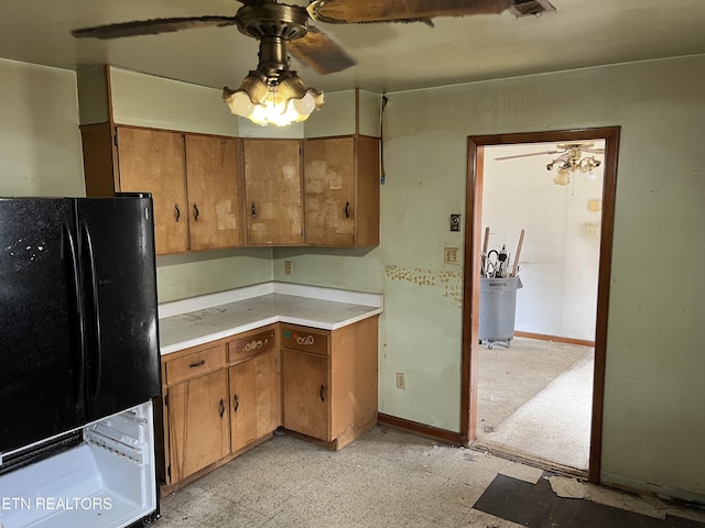 kitchen featuring light floors, light countertops, brown cabinets, freestanding refrigerator, and a ceiling fan