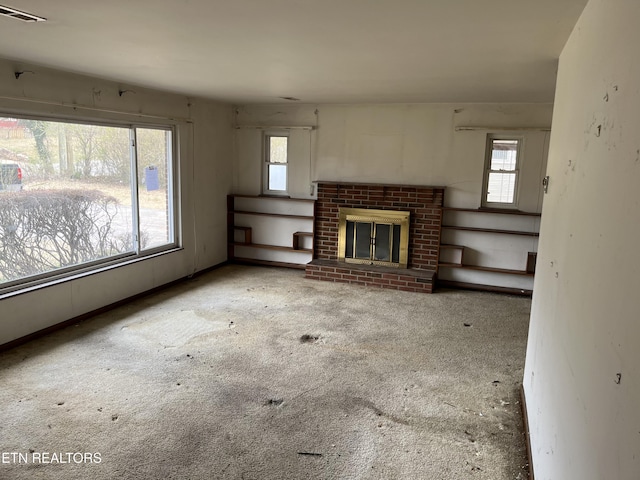 unfurnished living room with visible vents, a healthy amount of sunlight, and a brick fireplace