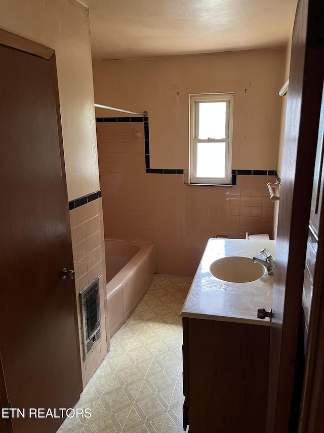 bathroom with heating unit, vanity, tile patterned floors, tile walls, and  shower combination