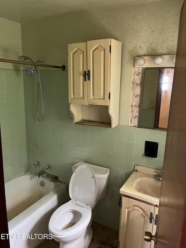 bathroom with vanity, tile walls, toilet, and shower / bath combination