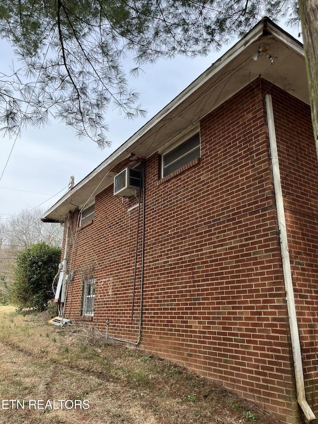 view of side of property featuring brick siding and a wall mounted air conditioner