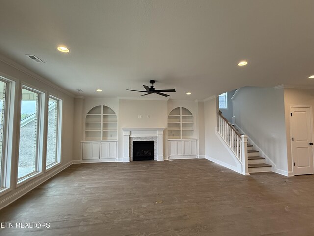 unfurnished living room with baseboards, visible vents, built in features, a ceiling fan, and crown molding