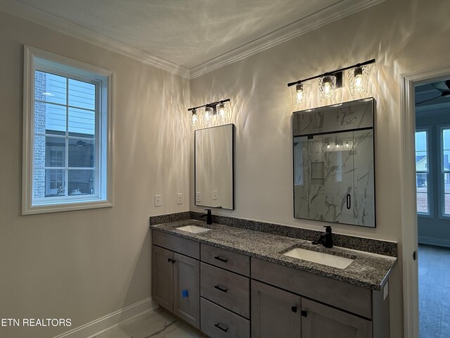 bathroom featuring baseboards, a sink, a marble finish shower, and double vanity