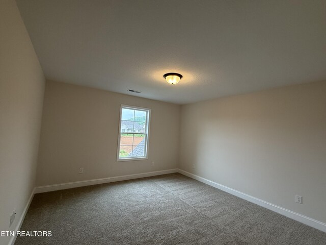 carpeted empty room featuring visible vents and baseboards