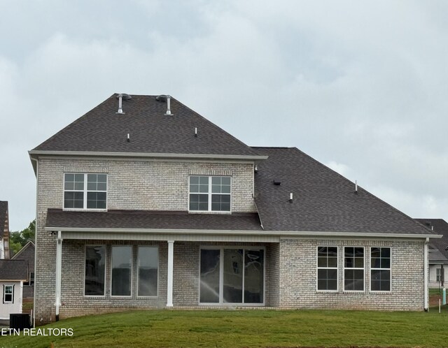 back of property with roof with shingles, a yard, and brick siding