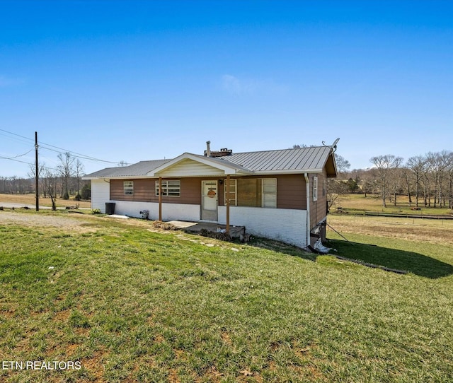 view of front of home with metal roof, brick siding, a front yard, and a standing seam roof