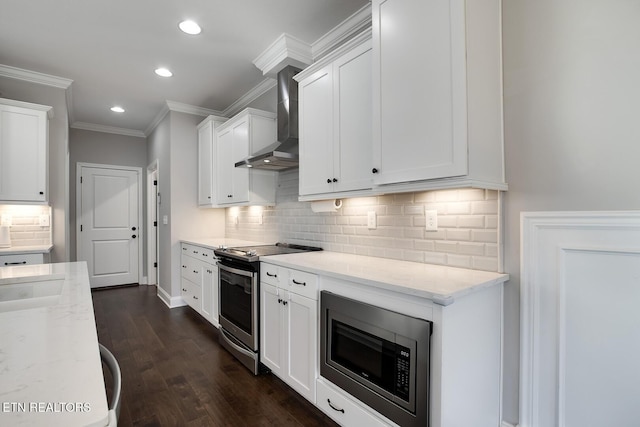 kitchen with white cabinets, appliances with stainless steel finishes, wall chimney exhaust hood, and light stone countertops