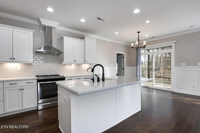 kitchen featuring visible vents, stainless steel range with electric stovetop, ornamental molding, a sink, and wall chimney range hood