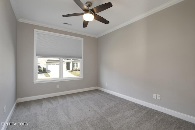 carpeted spare room with visible vents, baseboards, a ceiling fan, and crown molding