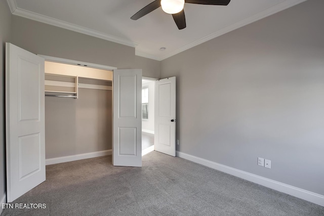 unfurnished bedroom featuring crown molding, baseboards, carpet floors, a closet, and a ceiling fan