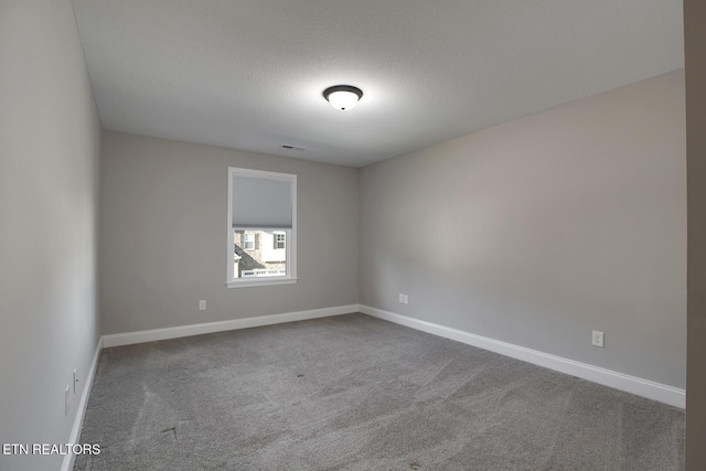 unfurnished room with visible vents, baseboards, carpet, and a textured ceiling