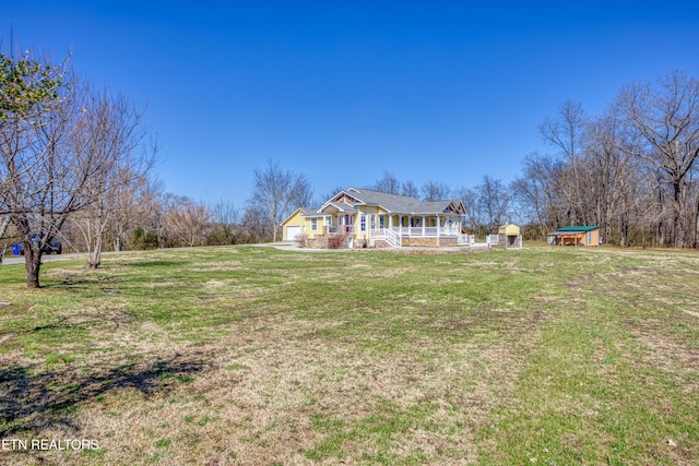 exterior space featuring an outbuilding, a porch, an attached garage, and a front yard