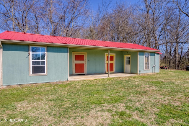 single story home featuring metal roof, a patio, and a front lawn