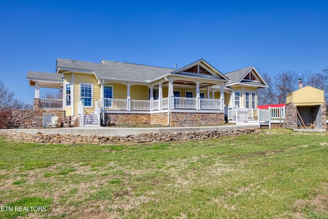 rear view of property featuring covered porch and a lawn