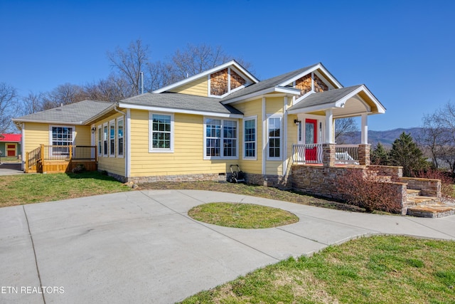 view of front of property featuring a porch, a front lawn, and roof with shingles