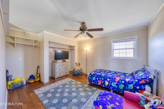 bedroom featuring a closet, a textured ceiling, wood finished floors, and crown molding