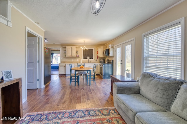 living area with crown molding, plenty of natural light, wood finished floors, and a textured ceiling