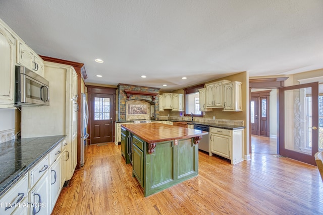 kitchen with light wood-style flooring, a kitchen island, recessed lighting, appliances with stainless steel finishes, and wooden counters