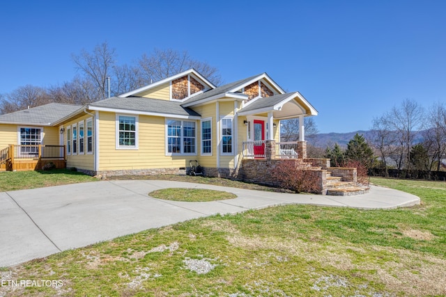 bungalow featuring a front lawn, a mountain view, driveway, and a shingled roof